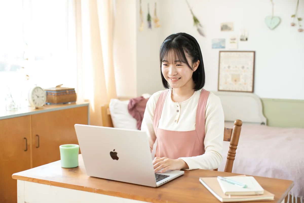 自宅の机でノートパソコンを使って学ぶ生徒